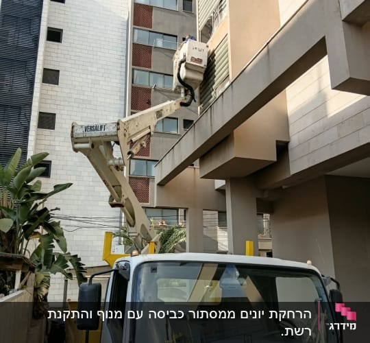 משאית עם מנוף ליד בניין מגורים